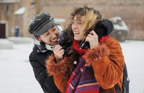 Two females joyously embracing in winter